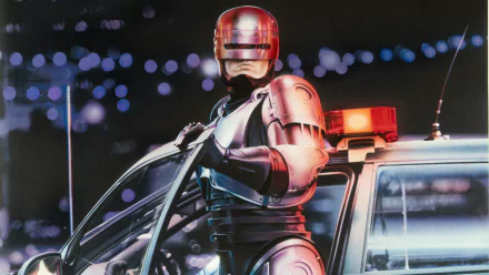 HD PC desktop wallpaper featuring RoboCop from the 1987 movie, standing next to a police car with city lights in the background.