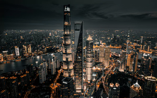 5K Ultra HD PC desktop wallpaper: Hong Kong cityscape at night, towering skyscrapers and a web of glowing streetlights and harbor reflections under a moody sky.