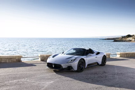 White Maserati MC20 sports car on a sunlit coastal road by the sea — 4K Ultra HD PC desktop wallpaper and background.