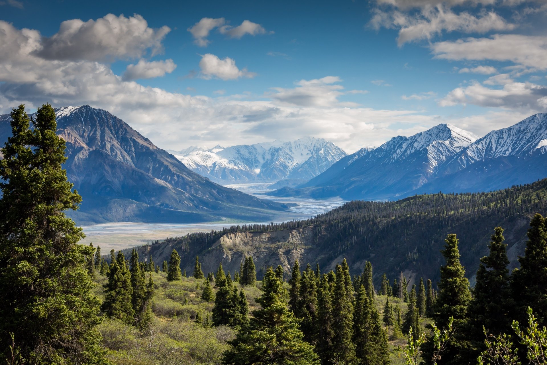 4K Ultra HD desktop wallpaper showcasing a stunning nature landscape of a lush valley framed by towering mountains under a partly cloudy sky.