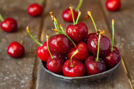 Close-up of dewy cherries piled in a small bowl on rustic wood — food, cherry; 2K Quad HD PC desktop wallpaper and background.