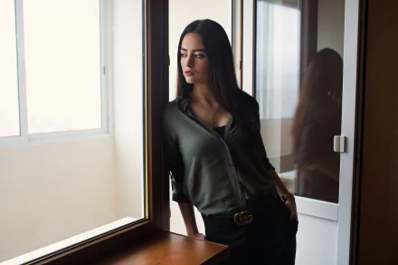 HD PC desktop wallpaper featuring a contemplative woman standing by a window, capturing a reflective and moody atmosphere.