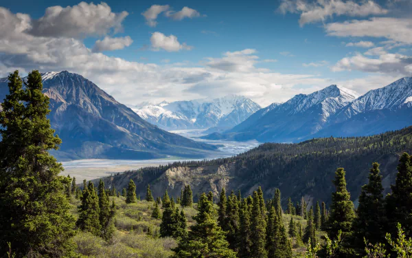 4K Ultra HD desktop wallpaper showcasing a stunning nature landscape of a lush valley framed by towering mountains under a partly cloudy sky.