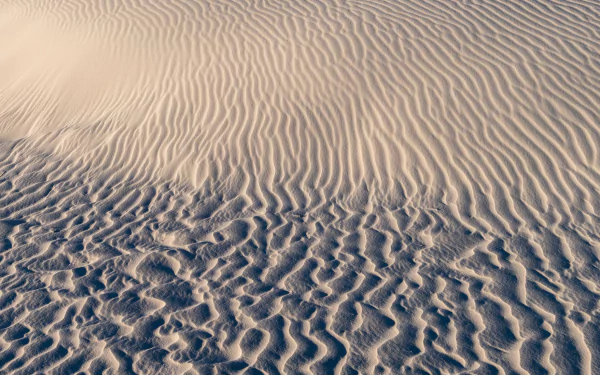 Sand dunes stretching across a vast desert landscape - perfect for a serene desktop wallpaper.