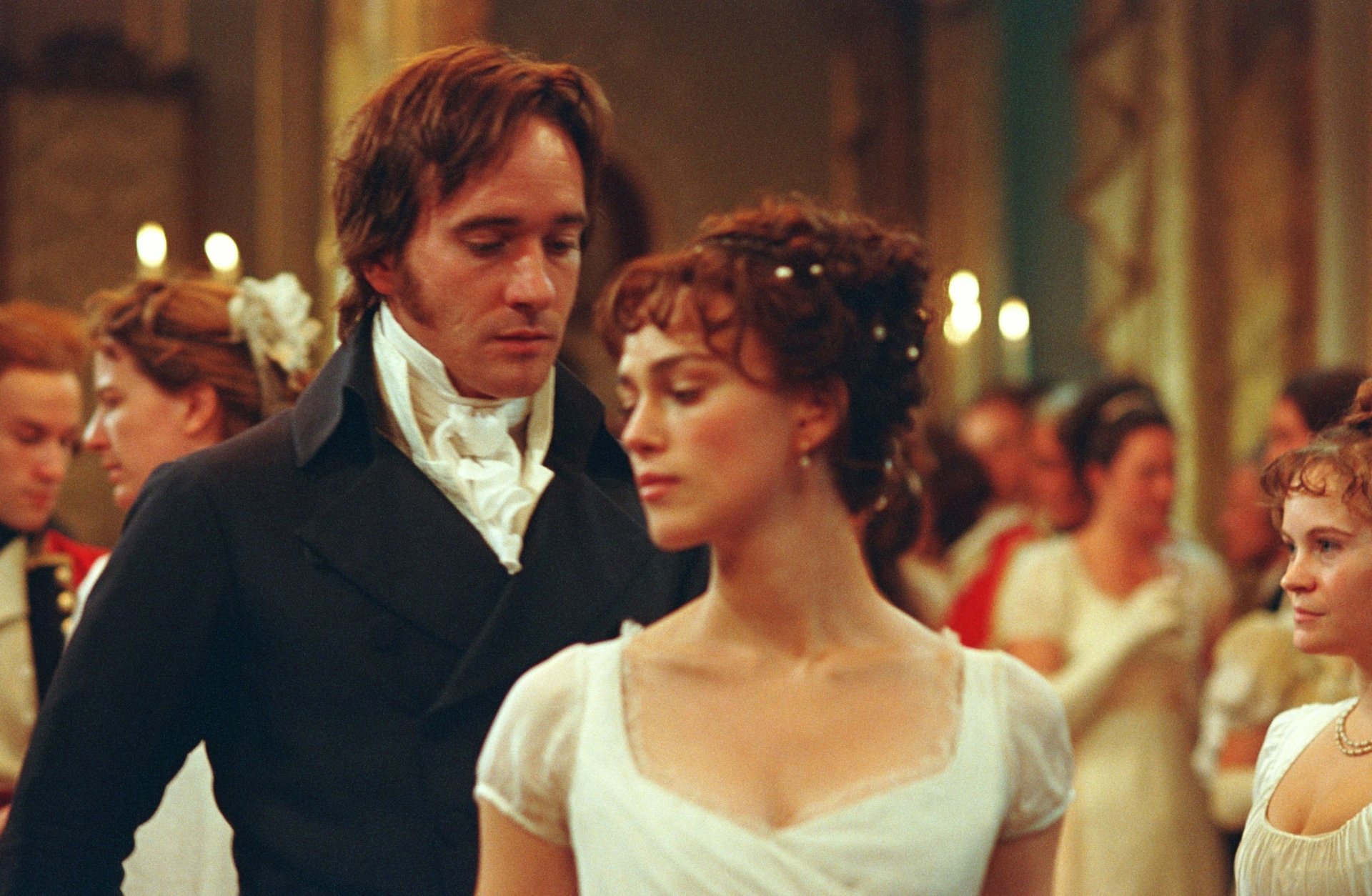 Candlelit Regency ball scene from the movie Pride & Prejudice: a man in a dark coat watches a woman in a white gown as they dance — 2K Quad HD PC desktop wallpaper/background.