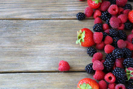 HD desktop wallpaper featuring a vibrant assortment of fresh strawberries, blackberries, and raspberries on a rustic wooden surface, highlighting colorful berries and food.