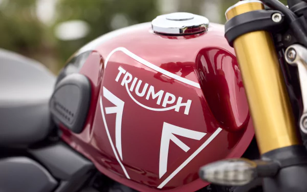 HD wallpaper featuring a close-up of a Triumph Speed 400 motorcycle tank, showcasing its red finish and iconic branding. A striking background for any motorcycle enthusiast.