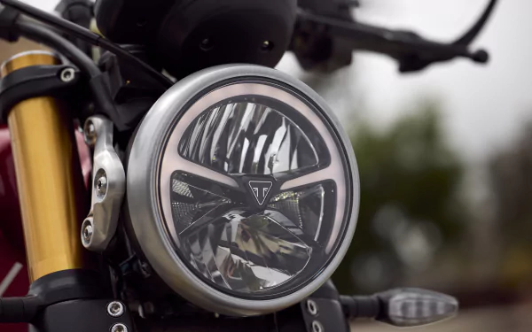 HD desktop wallpaper featuring the headlight of a Triumph Speed Triple 400 motorcycle with a blurred background.