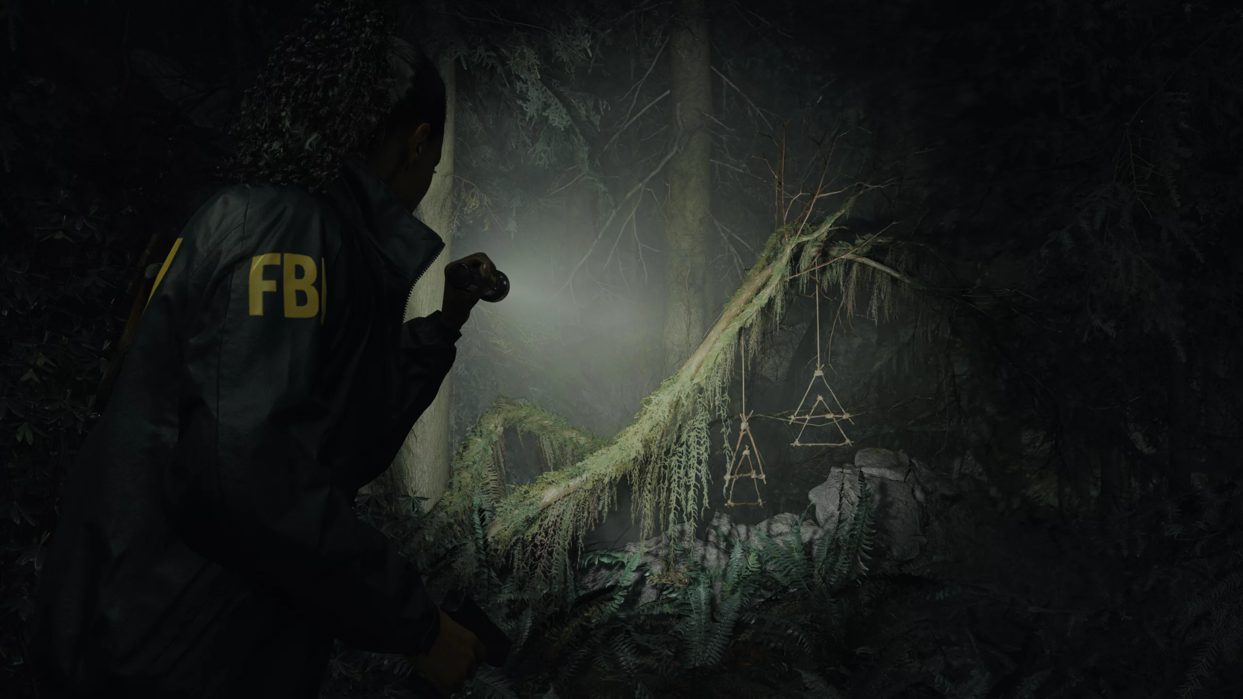 Alan Wake 2 HD wallpaper featuring a mysterious figure exploring a dark, eerie forest with supernatural elements.