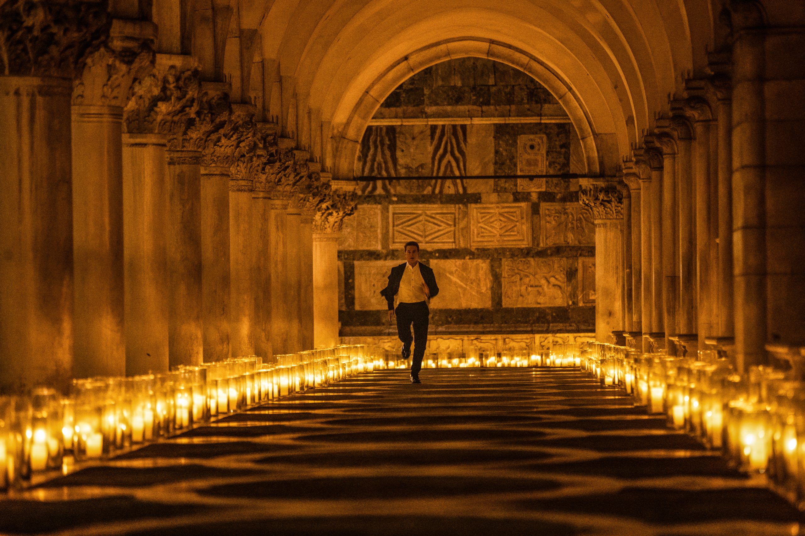 Silhouette of a person running through an ornate corridor lined with candles in a scene from Mission: Impossible - Dead Reckoning Part One, suitable for HD desktop wallpaper and background.