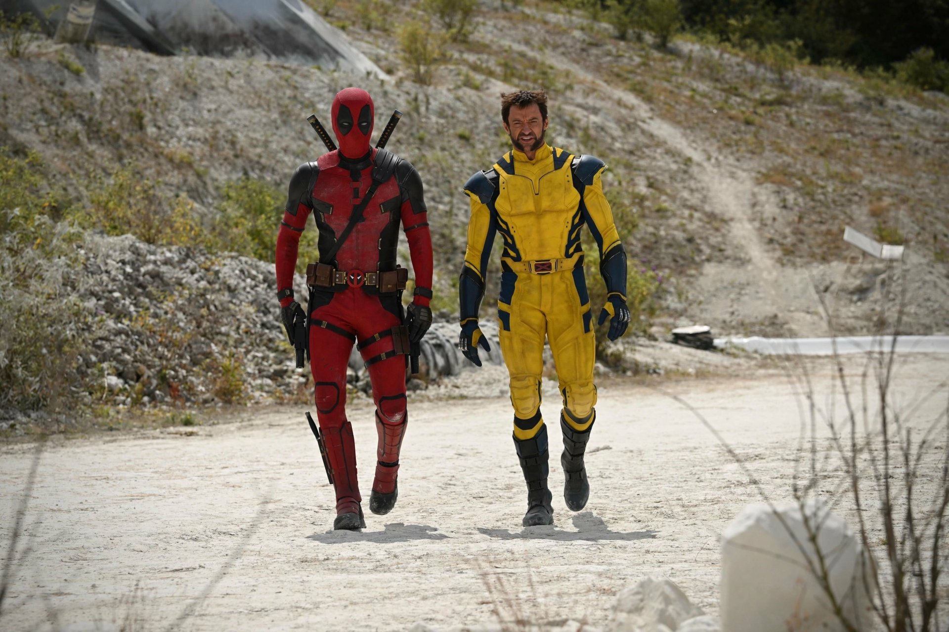 4K Ultra HD PC desktop wallpaper and background: movie image of Deadpool & Wolverine walking side-by-side on a sunlit dirt road, Deadpool in red and Wolverine in a yellow costume.