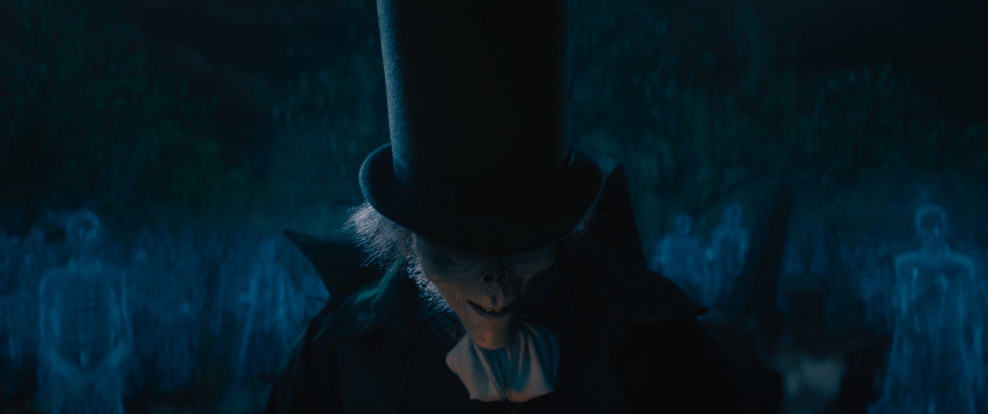 HD desktop wallpaper featuring a mysterious figure in a top hat from the movie Haunted Mansion, set against a shadowy, eerie forest background.