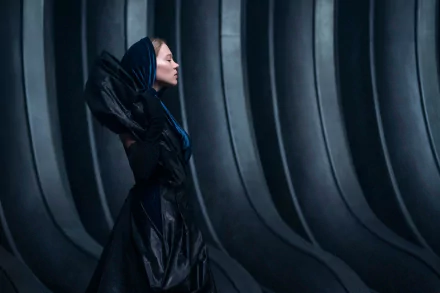 Dune Part Two HD Wallpaper Featuring a Female Character in a Futuristic Black Costume Against a Ribbed Backdrop