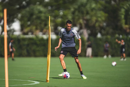 HD wallpaper of Sergio Busquets training with Inter Miami CF, focusing on dribbling around yellow poles on a lush green field.