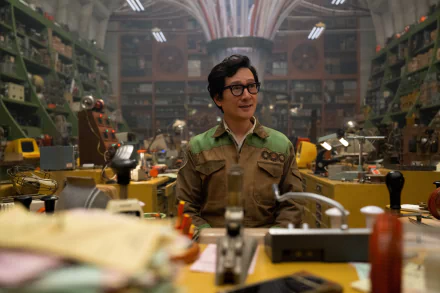 A character sits at a cluttered desk in a vibrant workshop, surrounded by various tools and gadgets, from Loki Season 2, providing an engaging HD background for fans of the TV show.