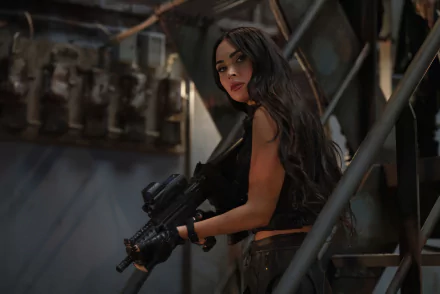 Megan Fox in a dynamic pose from the movie Expend4bles, holding a weapon and looking confidently over her shoulder, set against a detailed industrial background.