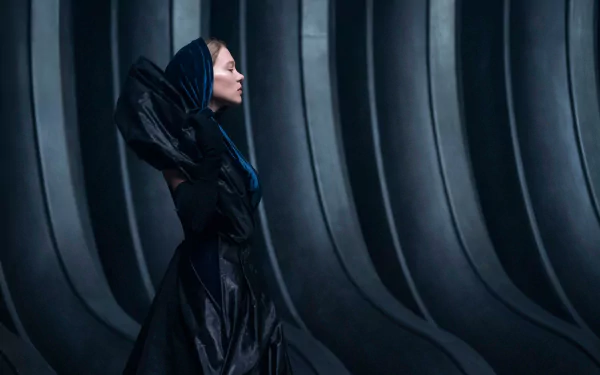 Dune Part Two HD Wallpaper Featuring a Female Character in a Futuristic Black Costume Against a Ribbed Backdrop