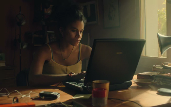 HD desktop wallpaper featuring a scene with a focused individual working on a laptop in a warmly lit room, evoking the atmosphere of Black Mirror.
