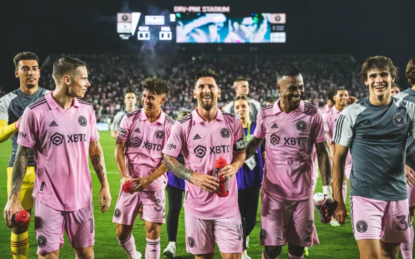 HD desktop wallpaper of Lionel Messi with Inter Miami CF teammates in pink jerseys, walking on the pitch at DRV PNK Stadium.