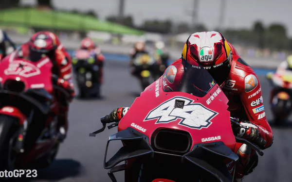 HD desktop wallpaper from the video game MotoGP 23 featuring a detailed scene of a motorcycle racer in the lead during a race, followed closely by competitors.
