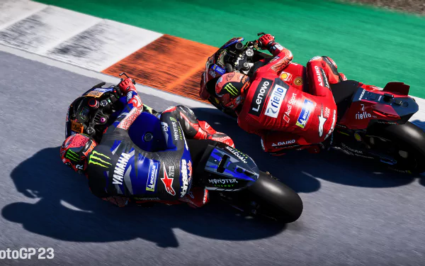 HD desktop wallpaper from the video game MotoGP 23 featuring two vibrant racing motorcycles in close competition on a race track.