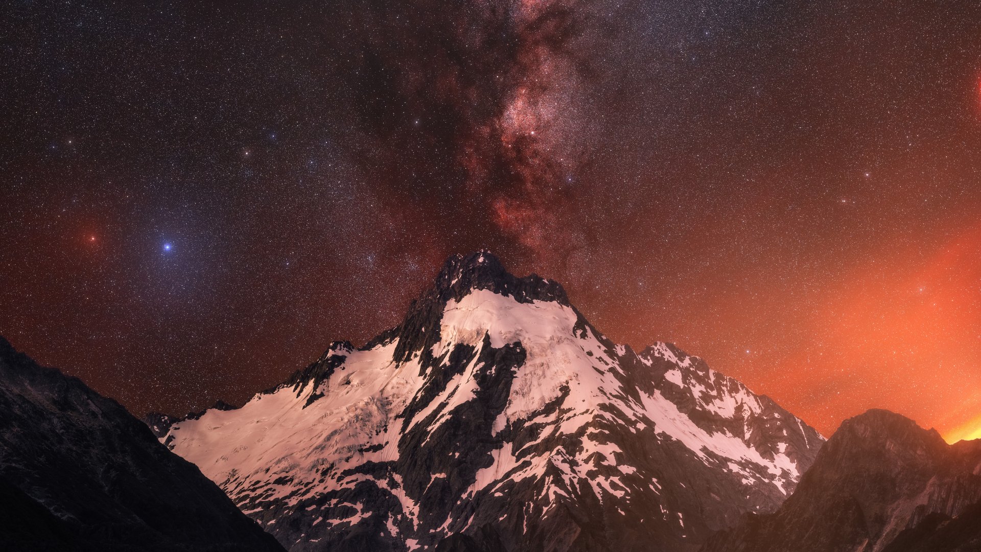 8K Ultra HD PC desktop wallpaper showcasing a snow-covered mountain peak beneath a stunning, star-filled night sky with vibrant orange and deep red hues.