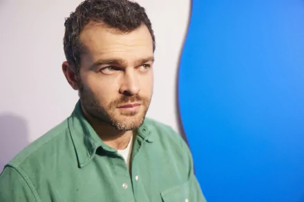 High-definition desktop wallpaper featuring a contemplative man in a green shirt against a blue and white background.