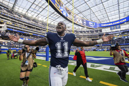 A jubilant Dallas Cowboys player celebrates on the field, arms raised, within a buzzing stadium backdrop. This vibrant HD wallpaper captures the excitement of sports.