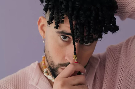 Stylish individual posing with a thoughtful expression for a high-definition desktop wallpaper with a soft purple background.