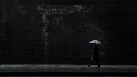 A person walks in a dark cityscape, holding a light-colored umbrella against a dramatic black backdrop, capturing a striking black aesthetic for a compelling desktop wallpaper.