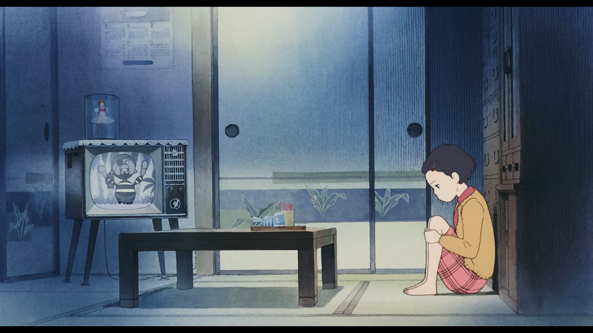 A calm, nostalgic scene from Studio Ghibli's Only Yesterday anime, showing a young girl sitting on the floor in a softly lit traditional Japanese room with an old TV.