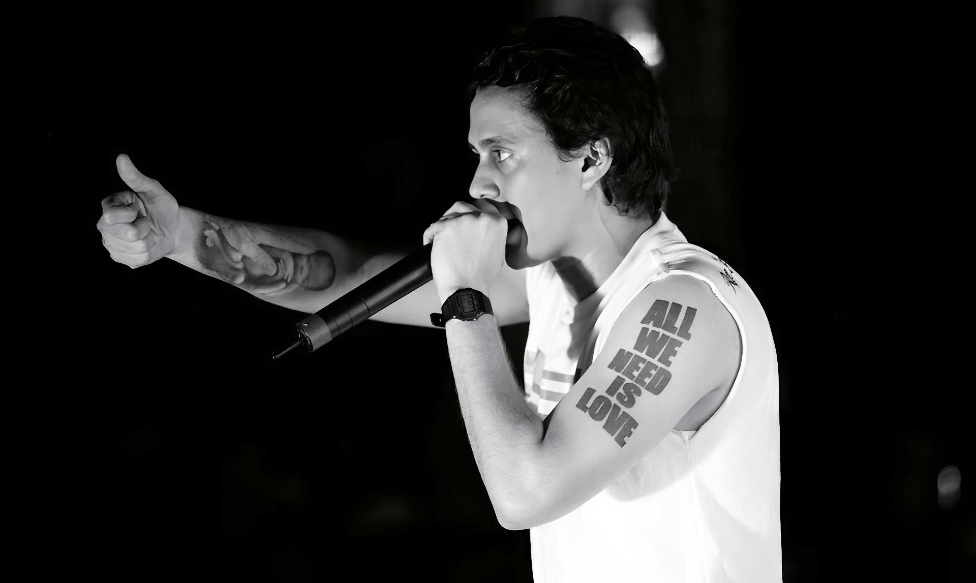 HD wallpaper featuring a musician on stage giving a thumbs-up, associated with Canserbero, set in a black and white tone for desktop backgrounds.