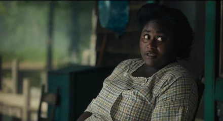 HD desktop wallpaper featuring a scene from The Color Purple (2023) movie with a woman in a vintage checkered dress looking contemplative.