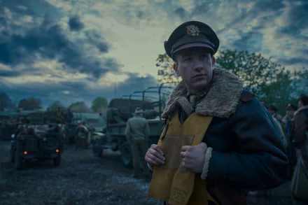 HD wallpaper of a scene from the TV show Masters of the Air featuring an officer in uniform with military vehicles in the background.