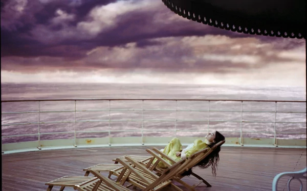 HD desktop wallpaper featuring a scene from the movie 'Poor Things' with a surreal atmosphere on a ship deck overlooking the sea.