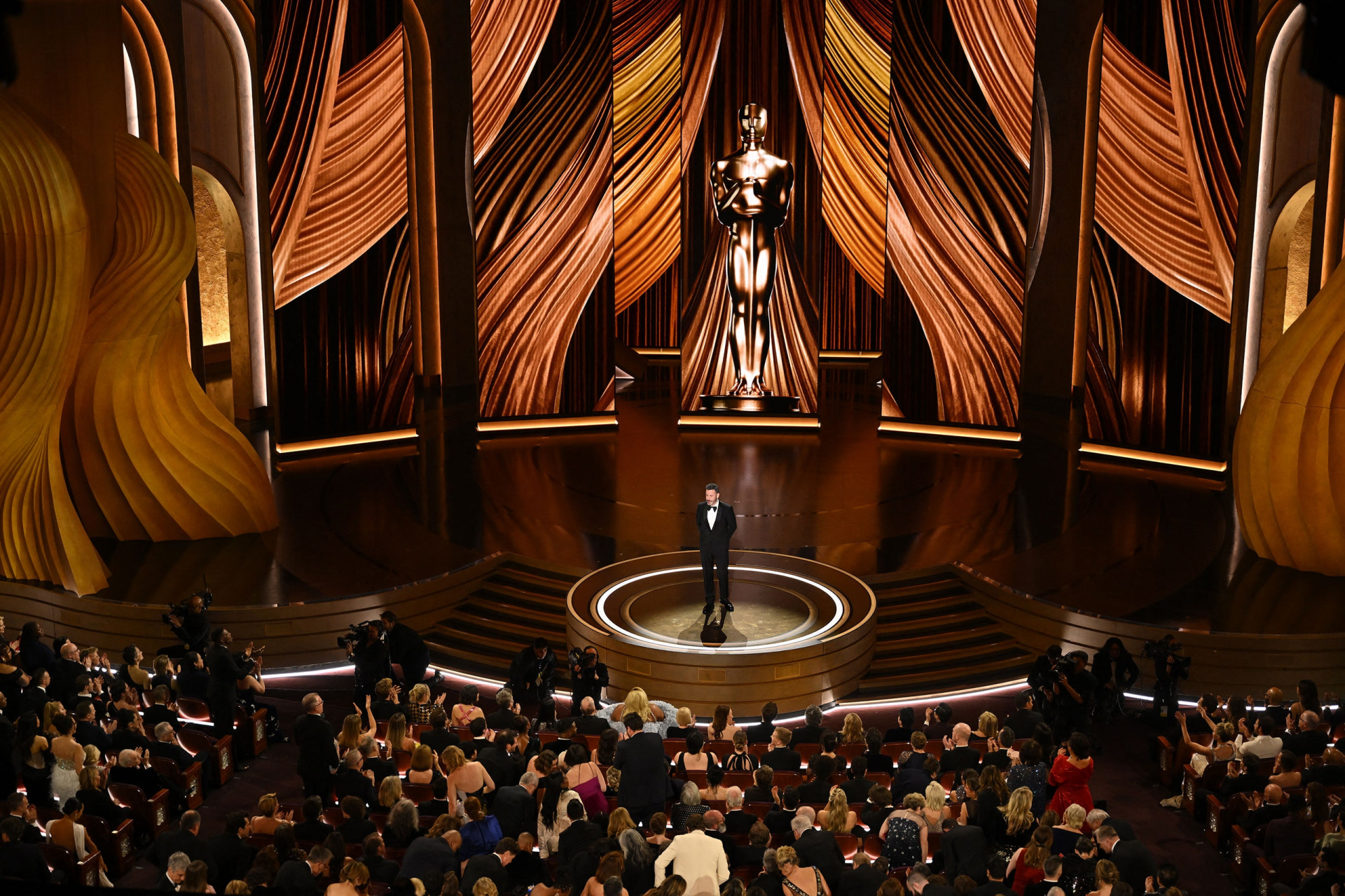 HD desktop wallpaper featuring an elegant scene from the Academy Awards (Oscars) with audience and a speaker on stage.