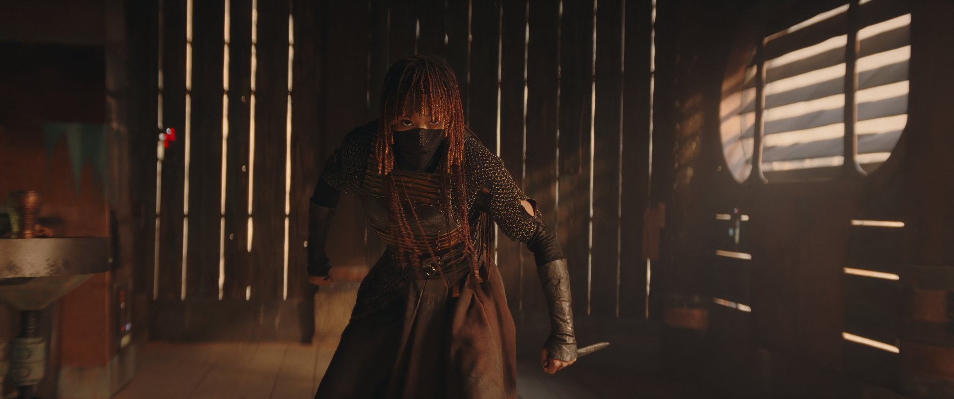 HD wallpaper featuring a scene from the TV show The Acolyte (2024) with a mysterious character in a dimly lit setting reminiscent of a starship or other futuristic interior.