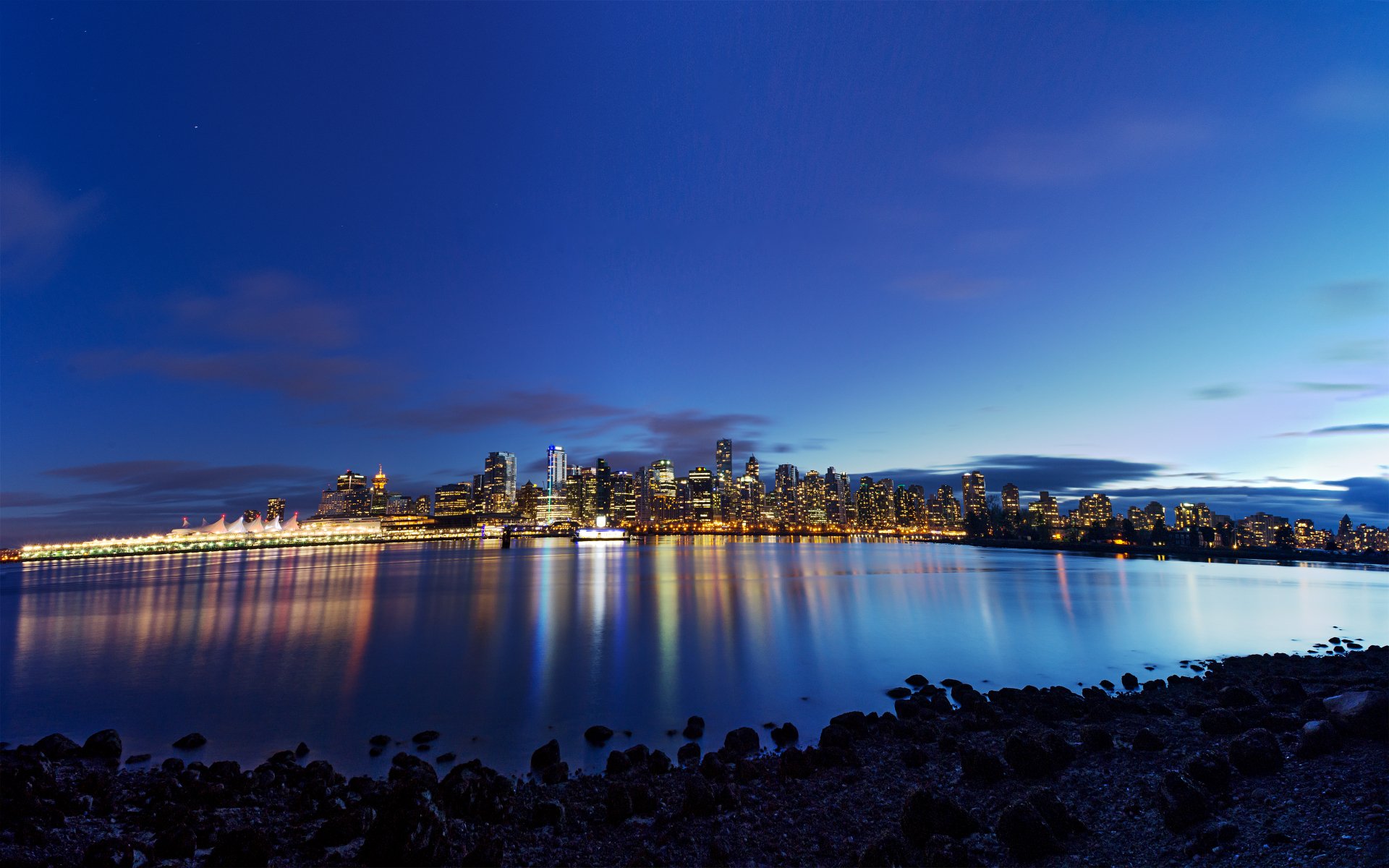 A stunning view of Vancouver's skyline at dusk, reflecting beautifully on the calm lake waters, showcasing the city's vibrant lights against a twilight sky.