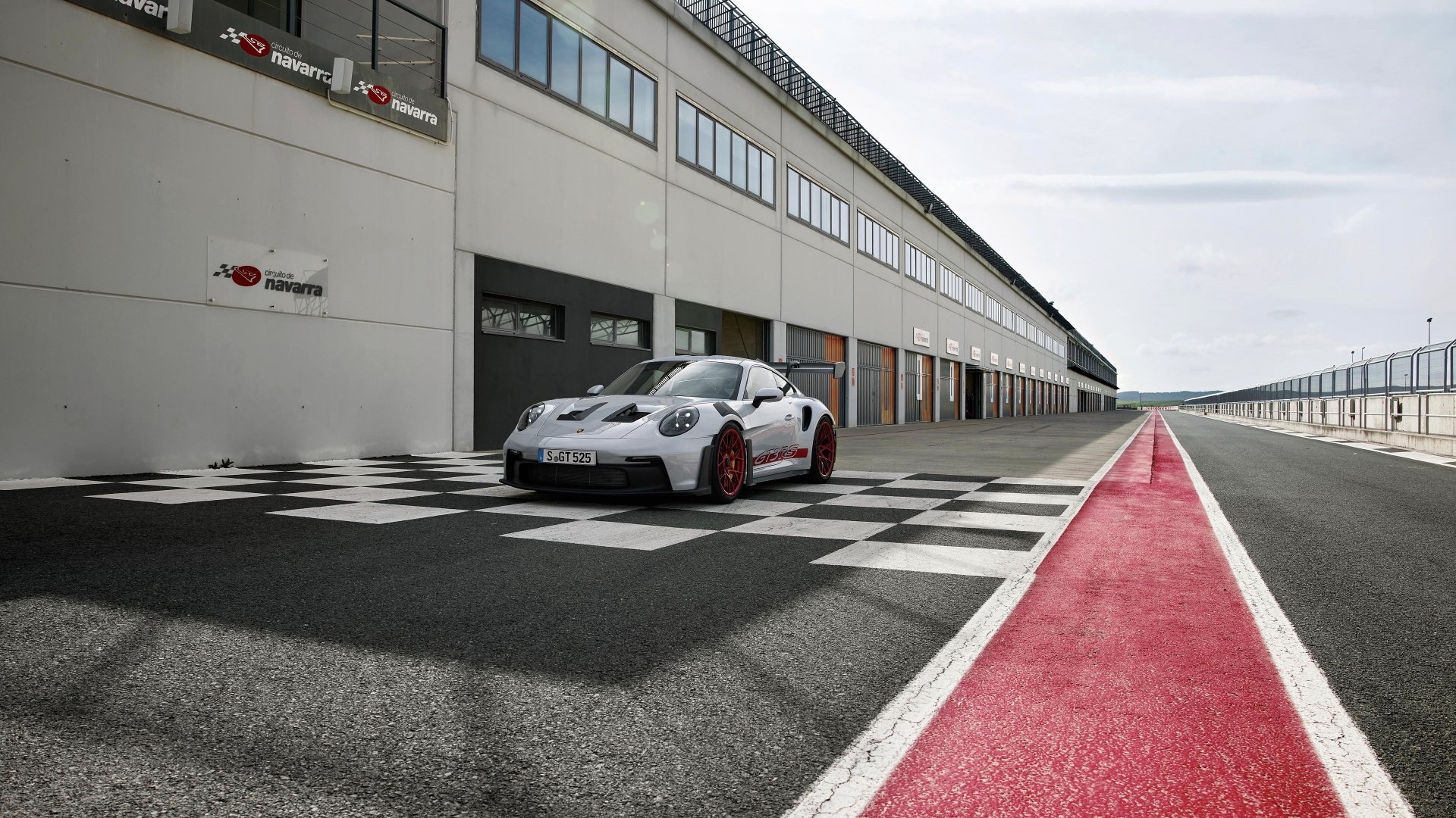 Porsche 911 GT3 RS parked on a race track pit lane with checkered pattern, suitable as HD wallpaper or background.