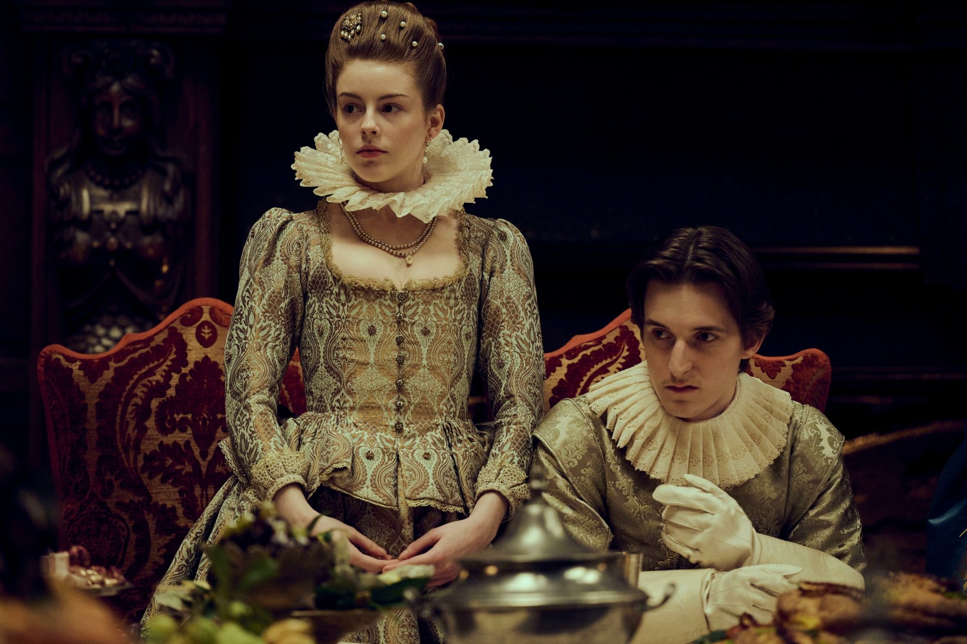 HD wallpaper of Mary & George from TV show, featuring two characters in period costumes sitting at a lavish dining table.