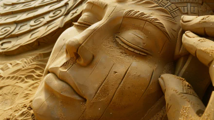 HD desktop wallpaper featuring detailed sand art of a serene face, exemplifying masterful sculpting skills.