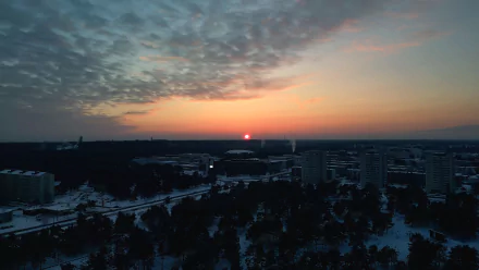 Sunset over snow-covered Tallinn, Estonia, captured in 4K Ultra HD with the sun glowing near the horizon and soft clouds scattered across the sky.