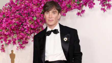 HD wallpaper featuring a person at the Academy Awards event, dressed in formal attire with a flower-filled backdrop.