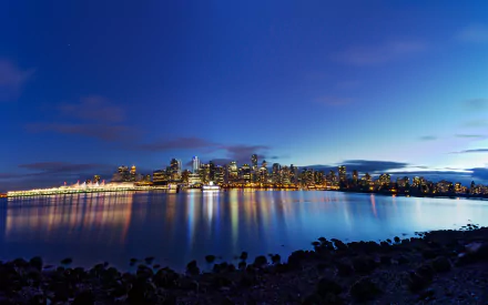 A stunning view of Vancouver's skyline at dusk, reflecting beautifully on the calm lake waters, showcasing the city's vibrant lights against a twilight sky.
