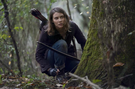 HD desktop wallpaper featuring a character from The Walking Dead TV show, stealthily crouched in a forest with a crossbow, ready for action.