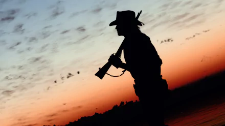 HD desktop wallpaper featuring a silhouette of a cowboy from Red Dead Redemption against a wild west sunset background.