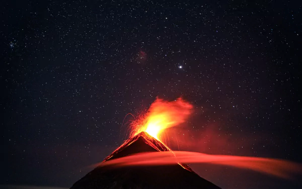 A 4K Ultra HD landscape wallpaper showing a glowing erupting volcano beneath a starry night sky with mountains silhouetted in the background.
