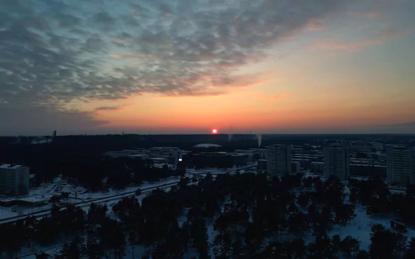 Sunset over snow-covered Tallinn, Estonia, captured in 4K Ultra HD with the sun glowing near the horizon and soft clouds scattered across the sky.