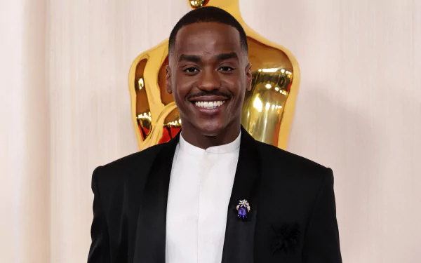 HD desktop wallpaper featuring Ncuti Gatwa at the Academy Awards, posing with an Oscars statue in the background.