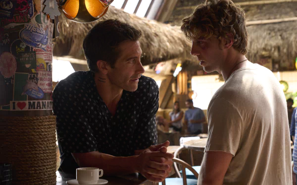 HD wallpaper featuring a scene from the movie Road House (2024) with Jake Gyllenhaal conversing with another character in a tropical bar setting.